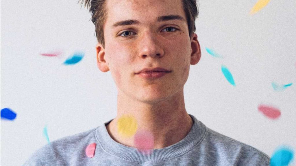 A male standing and looking straight ahead while confetti falls over him