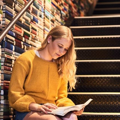 Female student sitting on the steps reading a book