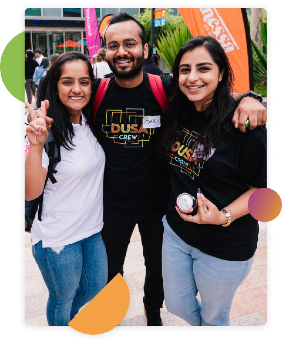 Three DUSA Crew volunteers standing together arm in arm and smiling