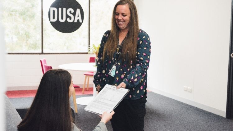 Advocacy staff member smiling and handing papers to a student