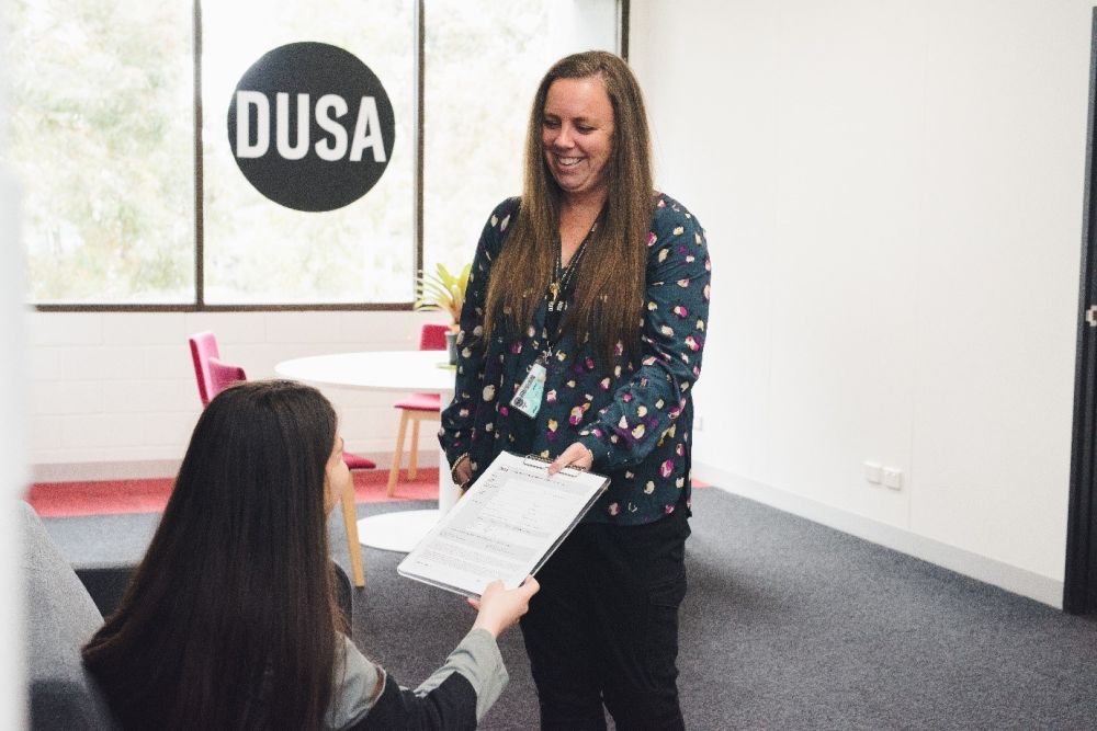 Advocacy staff member smiling and handing papers to a student