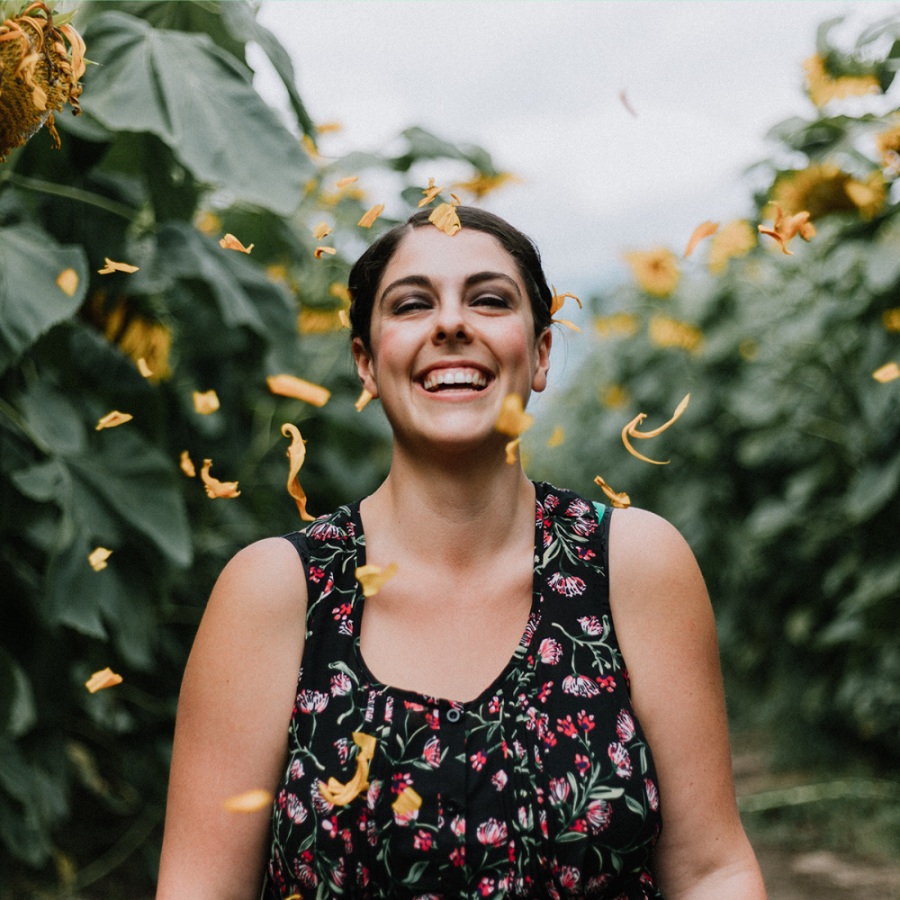 Female smiling with joy as she walk through a path surrounded by greenery