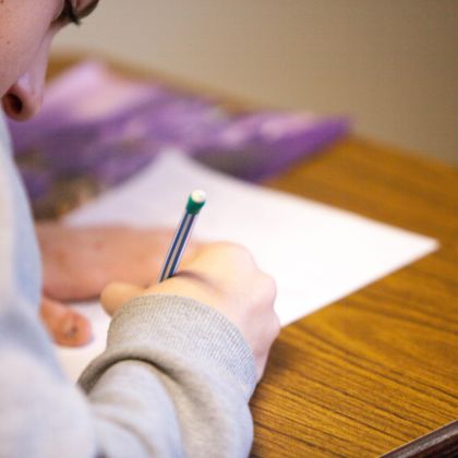 Student sitting at desk concentrating as he writes notes