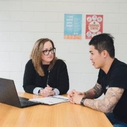 Advocacy Support staff member sitting at a desk talking with a male student
