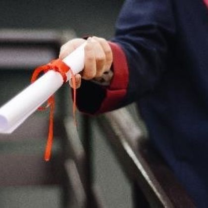Student dressed in graduation gown with certificate in hand