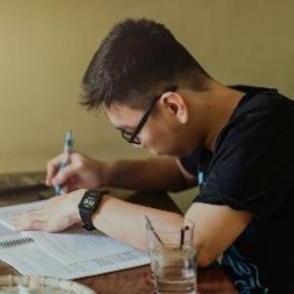 male student sitting at a desk studying and writing notes