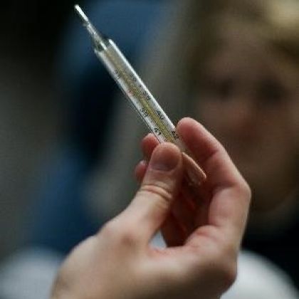 A person holding a thermometer after taking someones temperature