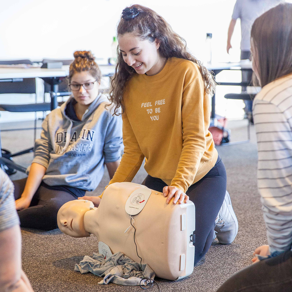 Female student practicing practicing resuscitation on CPR maniken in her first aid class