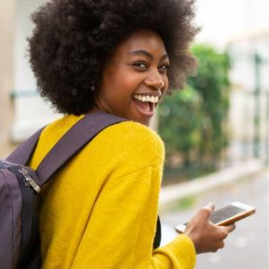 Female with a large afro carrying a backpack with a big smile on her face