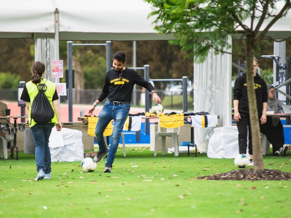Male student kicking a ball along the grass