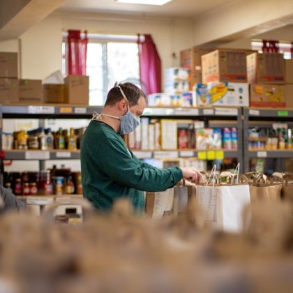 photo of a man wearing a mask and an apron packing food bags