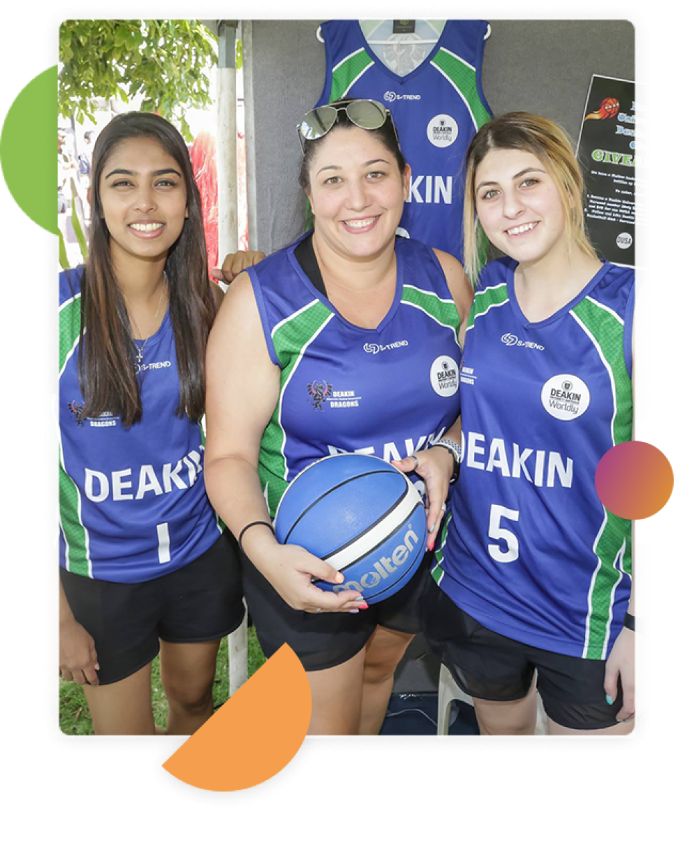 Three female students in blue jerseys the girl in the middle holding a blue basketball