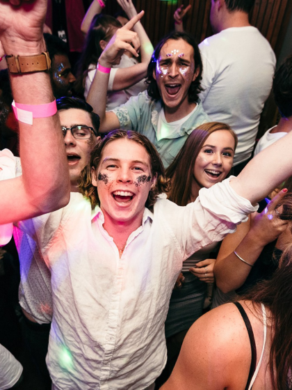 A group of young adults celebrating, all wearing glitter make up