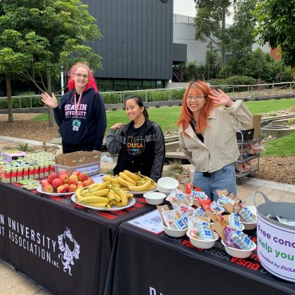 Advocates and volunteers handing out free breakfast on Burwood campus, smiling and waving