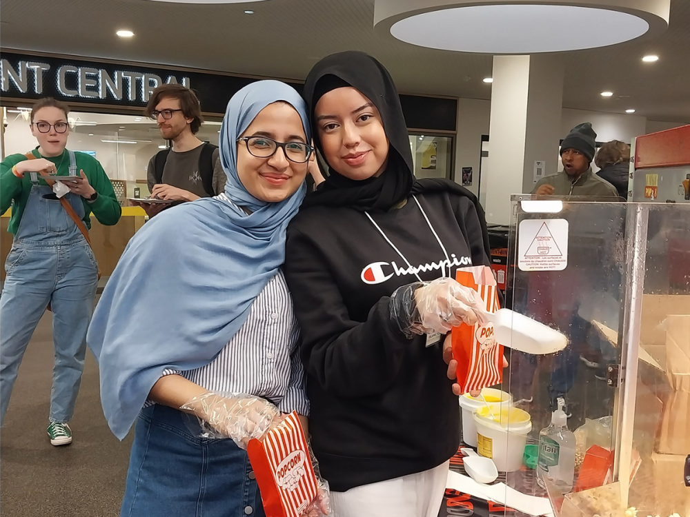 Two girls handing out popcorn at Student Central Burwood, smiling