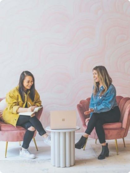 Two female students sitting on chairs and talking to each other