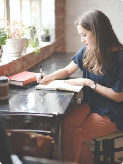 Female sitting at a bench writing in a text book
