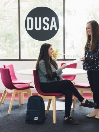 Advocacy staff member talking to a student sitting in a chair and looking at document